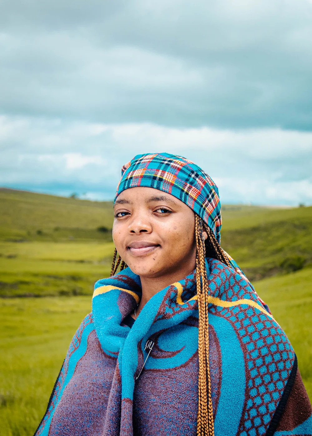 A woman wrapped in a traditional blanket standing on green hills in the Eastern Cape (representative photograph, not Lesedi's own homestead)